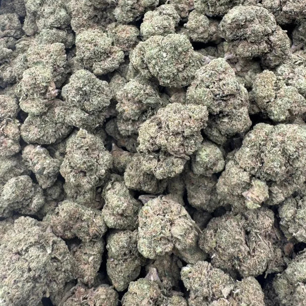 Close-up of a pile of green cannabis buds on a reflective surface