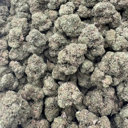 Close-up of a pile of green cannabis buds on a reflective surface