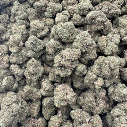 Close-up of a pile of green cannabis buds on a reflective surface