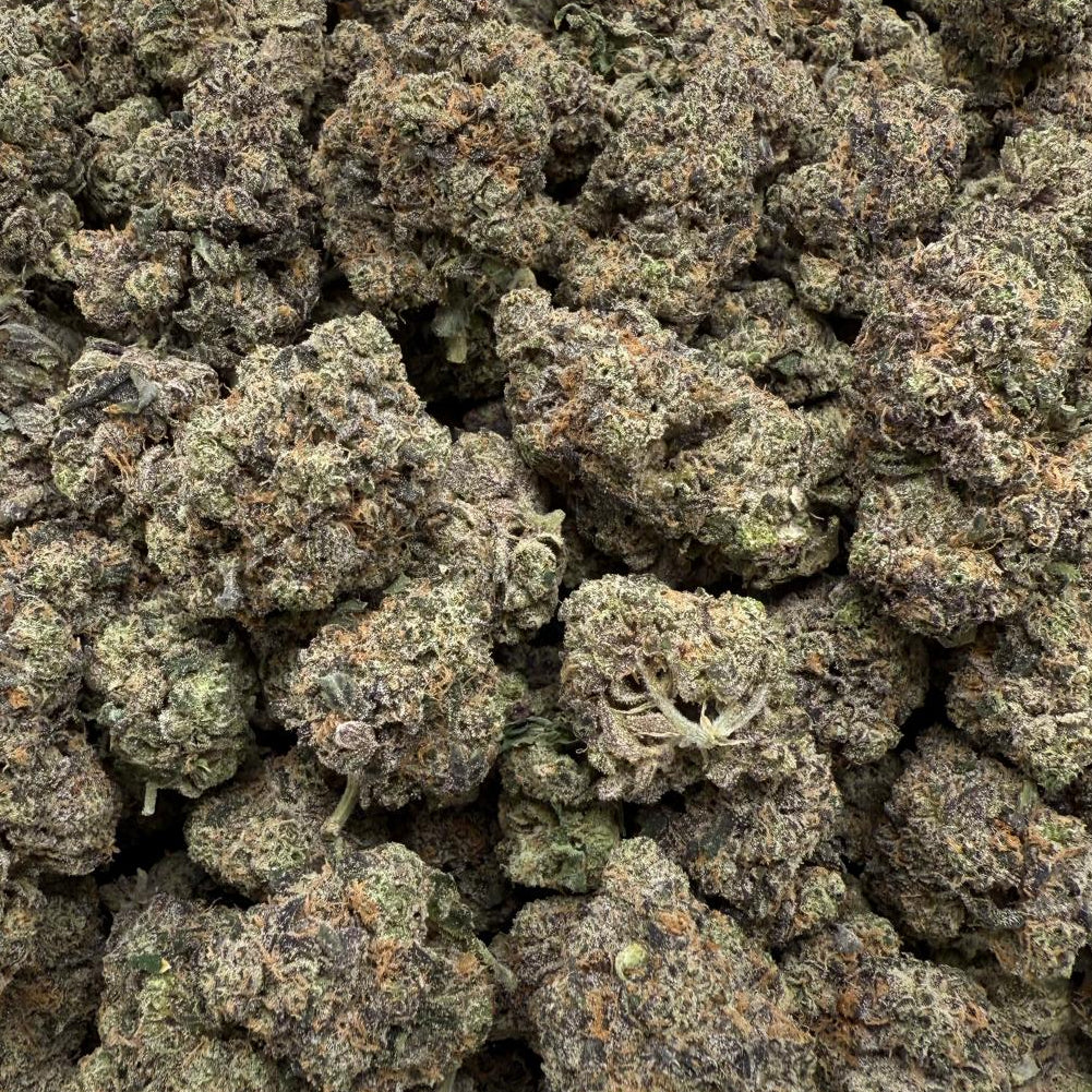 Close-up of a pile of dried cannabis buds on a clear plastic surface.
