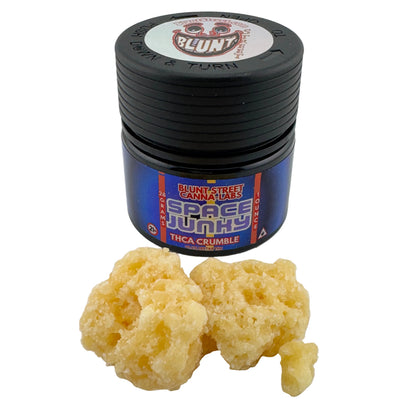 Black container labeled 'Space Junky' with THC crumble on a white background