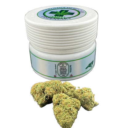 White container with green label on a black surface with cannabis buds.