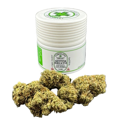 Bunch of green cannabis buds in front of a white container with green label on a gray background