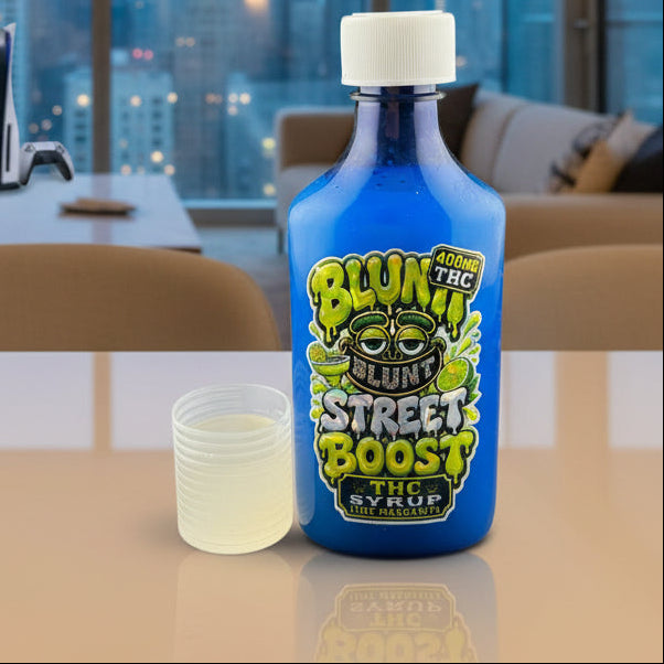 A blue bottle of Blunt Street Boost THC Syrup with a white cap, shown next to a small clear plastic cup containing a pale yellow liquid on a dark gray background.