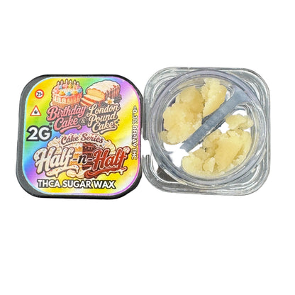 A square metal tin of 'Birthday London Cake & Pound Cakes' Half-n-Half THCA sugar wax next to an open clear plastic container showing the pale yellow wax crystals inside, set on a dark gray surface.