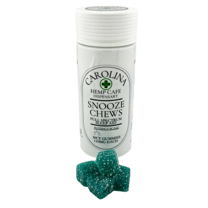 A bottle of Carolina Hemp Cafe's Snooze Chews, Full Spectrum Sleep Aid, with a couple of blue gummy chews displayed in front.